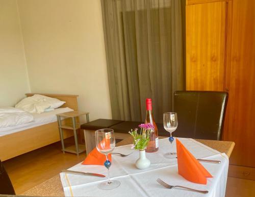 a dining table with a bottle of wine and glasses at Ride & Rest, Budget, Waschmaschine, Wohnzimmer, Küche, Radlgarage in Altötting