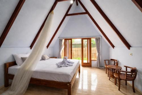 a bedroom with a bed and a table and chairs at Harmony Beachfront Bungalow in Gili Meno
