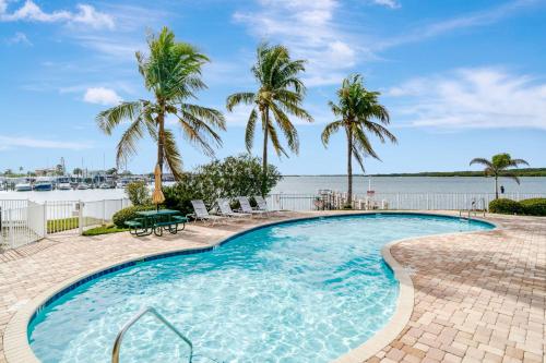a swimming pool with palm trees and a body of water at Sunsets Waterview Balcony King Bed & Heated Pool in St. Petersburg