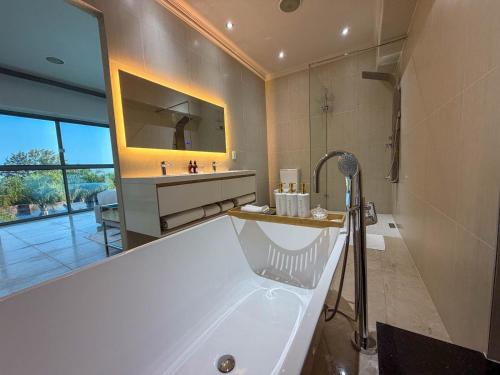 a bathroom with a large tub and a large mirror at Silva Villa in Bedfordview