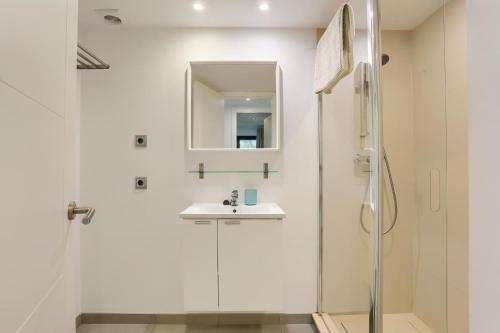 a white bathroom with a sink and a shower at La Perla 3 in El Port