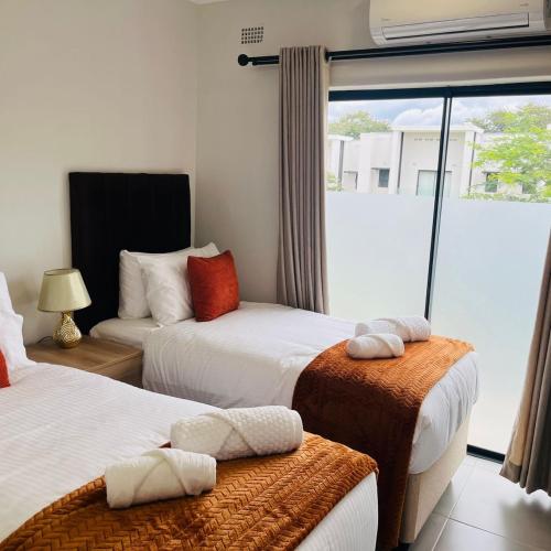 a hotel room with two beds and a window at 219 Contours Luxury Apartment in Victoria Falls