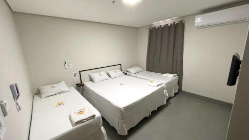 una stanza con due letti e una televisione di Hotel Fly - Aeroporto Cuiabá a Várzea Grande