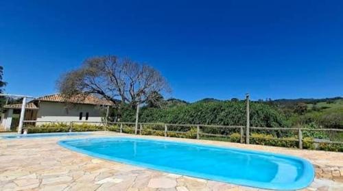 a blue swimming pool in a yard with a fence at Pousada Vison in Itapeva