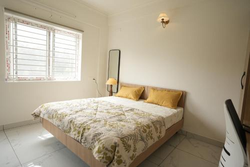 a bedroom with a large bed with yellow pillows at HomeSlice Sarjapur - Balcony Rooms in Bangalore