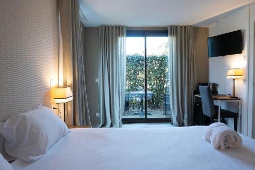 a hotel room with a bed and a large window at Hôtel Les Muses in Annecy