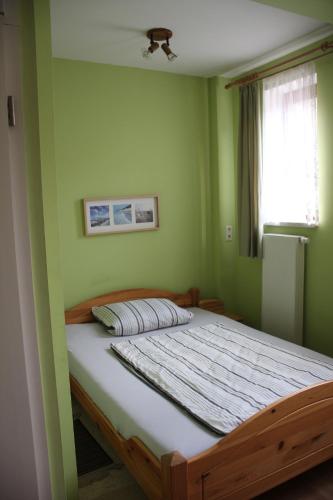 a bedroom with a bed with green walls and a window at Ferienhaus Grasse in Görlitz
