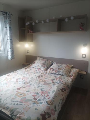 a bed with a floral comforter in a bedroom at camping les oyats in Seignosse