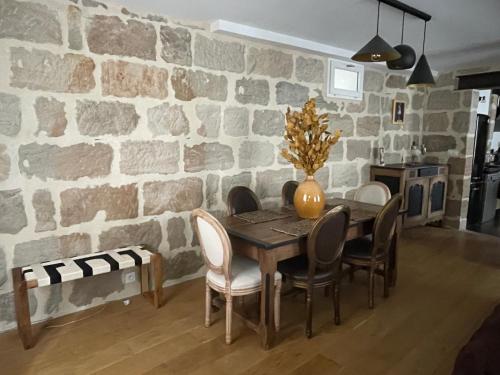a dining room table with chairs and a stone wall at appartement de charme centre historique de Brive in Brive-la-Gaillarde