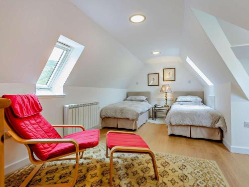 a attic bedroom with two beds and a red chair at 1 Bed in Ardross oc-95533 in Alness