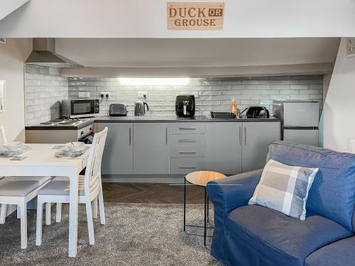 a living room with a blue couch and a kitchen at Lily - Uk49362 in Bridlington