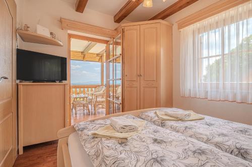 a bedroom with a bed and a television and a balcony at Vineyard Cottage Stepan in Črnomelj