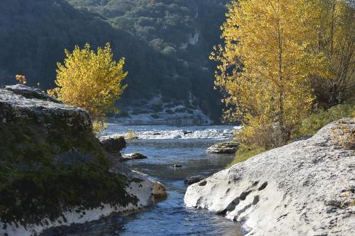 a river with rocks and trees in the background at Le Mas des Alexandrins in Uzès