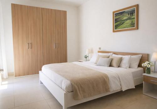 a bedroom with a large white bed with a wooden cabinet at Adamo ed Eva Resort in Numana