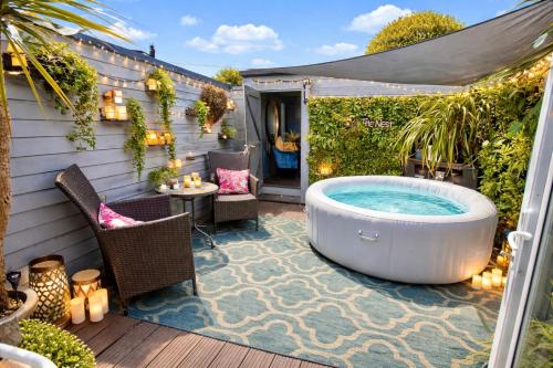 a hot tub on a patio with a table and chairs at A Hidden Gem With Private Hot Tub and Garden - Netflix - Fast Wifi - Free Parking in Bournemouth