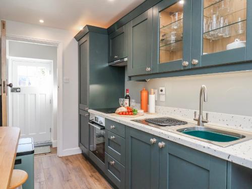 a kitchen with blue cabinets and a sink at Holly Cottage in Whitby