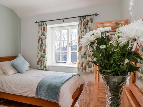 a bedroom with a bed and a vase with flowers on a table at Holly Cottage in Whitby