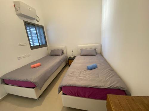 two twin beds in a room with a window at Penthouse à Manhattan Netivot in Netivot
