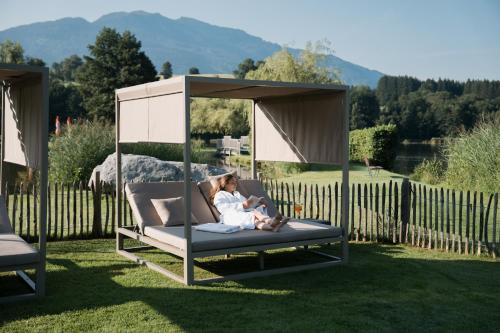 a woman sitting on a swing in a yard at Ritzenhof - Hotel und Spa am See 4-Sterne-Superior in Saalfelden am Steinernen Meer