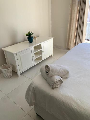 a white bedroom with a bed with towels on it at Villa Ti Amo Flat in Ramsgate