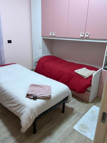a small room with two beds with red sheets and cabinets at Sabry house in Novi Ligure