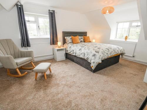 a bedroom with a bed and a chair at Long Barn in Bridport