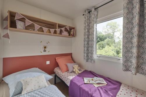 a small bedroom with two beds and a window at Camping Bel Air - Cancale in Cancale