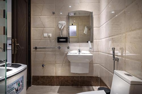 a bathroom with a sink and a toilet and a mirror at Rasis Serviced Apartments in Jeddah