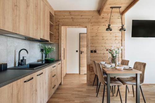 a kitchen with wooden cabinets and a table with chairs at Apres Ski Bachleda in Zakopane