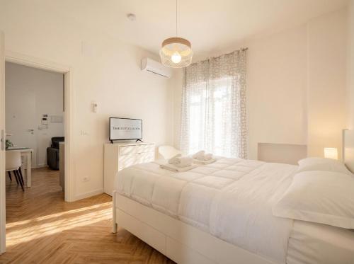 a white bedroom with a large white bed and a window at LARI - appartamento moderno in centro in Bari