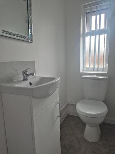 a white bathroom with a toilet and a sink at 3 bedroom house-Ellesmere Port in Ellesmere Port