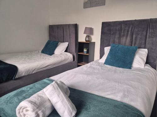 two beds with towels on them in a room at 3 bedroom house-Ellesmere Port in Ellesmere Port
