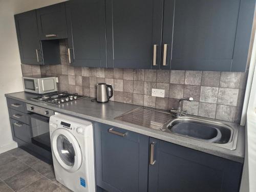 a kitchen with a sink and a washing machine at 3 bedroom house-Ellesmere Port in Ellesmere Port