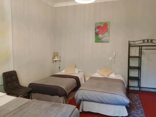a room with three beds and a chair at Auberge Cocagne in Avèze