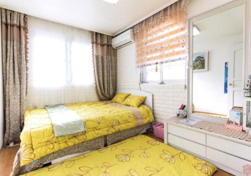 a bedroom with a yellow bed and a window at Homestay Eve in Seoul