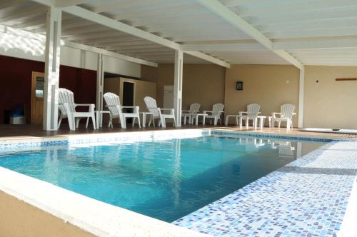 a large swimming pool with white chairs and chairs at Chacras del Mar in Mar Azul
