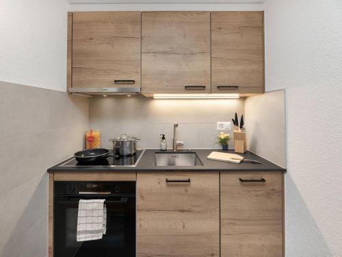 a kitchen with wooden cabinets and a sink at Apartment Baroudeur B04 by Interhome in Verbier
