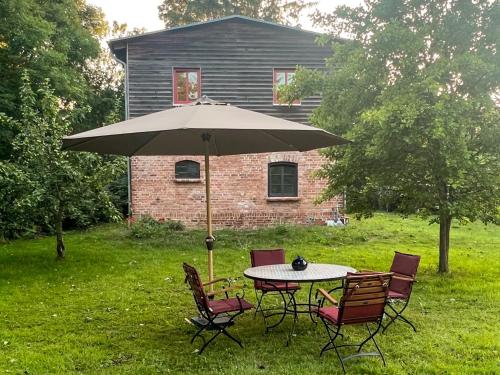 a table and chairs with an umbrella in front of a house at Gästescheune Rubitz in Rubitz