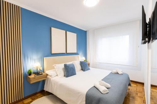a bedroom with a bed with a blue accent wall at Terraza, 20min playas, 5min Pontevedra, Garaje in Pontevedra