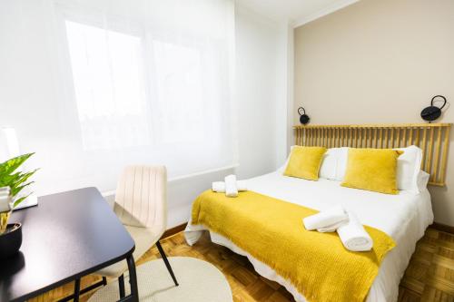 a bedroom with a bed with yellow sheets and a desk at Terraza, 20min playas, 5min Pontevedra, Garaje in Pontevedra