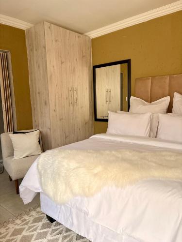 a bedroom with a large white bed and a chair at Ring Road Guesthouse in Vereeniging