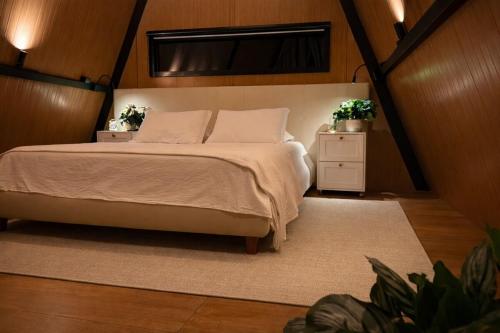 a bedroom with a bed and two night stands with plants at Cabana Escandinávia Praia de Fora in Palhoça