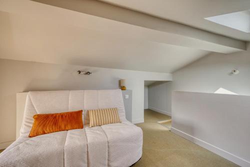a bedroom with a white bed with an orange pillow at La maisonnette - 4 pers - Centre ville - télétravail in Angoulême