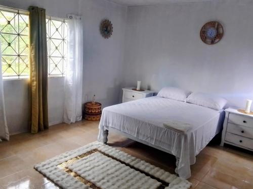 a white bedroom with a bed and a window at Irie Bamboo in Bamboo