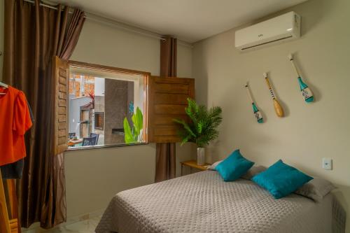 a bedroom with a bed with blue pillows and a window at Renner Ventos praia do Preá Casa Completa com Piscina in Cruz