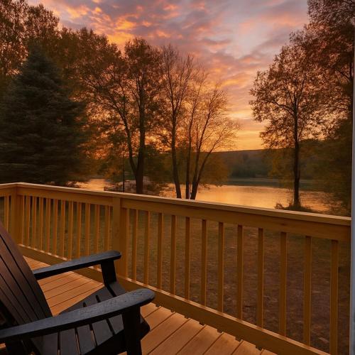 a rocking chair on a deck with a view of a lake at Romantic Riverfront Retreat in Sugar Run