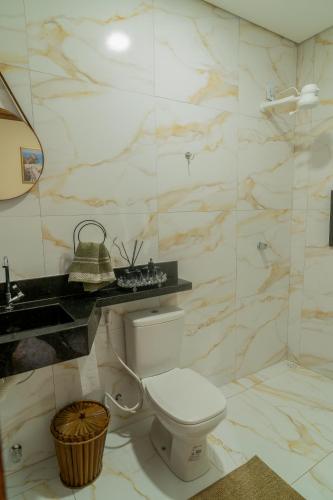 a white bathroom with a toilet and a sink at Renner Ventos praia do Preá Casa Completa com Piscina in Cruz