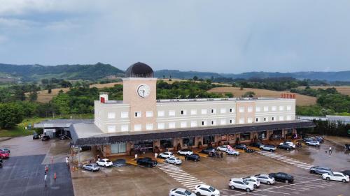 a large building with a clock tower in a parking lot at Rodoserv Hotel in Pardinho