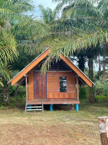 a small wooden house with a palm tree at บากันใหญ่โฮมสเตย์ in Ban Ba Kan Yai