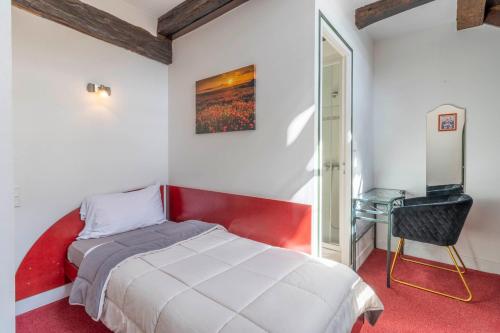 a bedroom with a bed and a desk and a television at Hôtel Jean XXII in Cahors